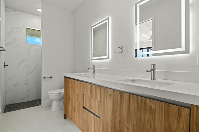 bathroom featuring toilet, vanity, and tiled shower