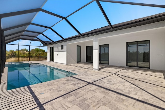 view of pool with glass enclosure, an in ground hot tub, and a patio area