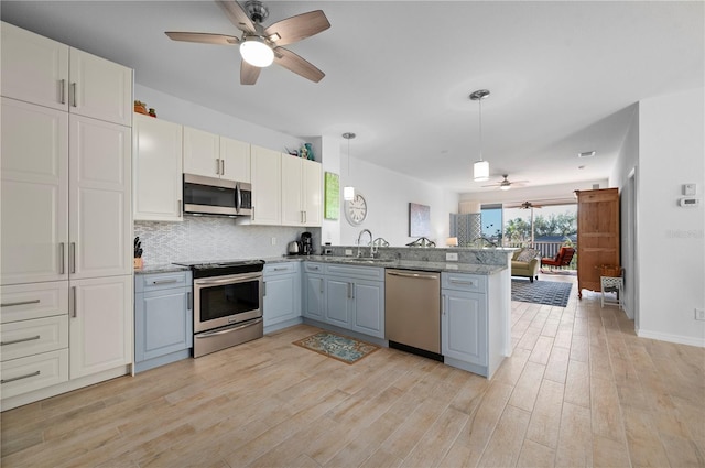 kitchen featuring white cabinetry, sink, hanging light fixtures, kitchen peninsula, and appliances with stainless steel finishes