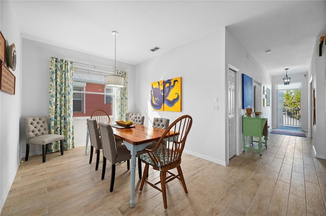 dining space with light wood-type flooring and an inviting chandelier