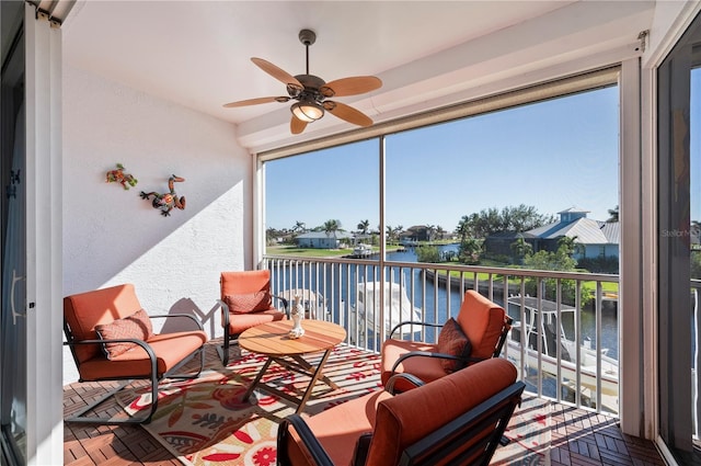 sunroom featuring ceiling fan, a healthy amount of sunlight, and a water view