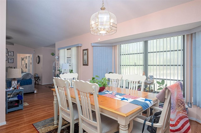 dining space featuring a chandelier, hardwood / wood-style floors, and vaulted ceiling