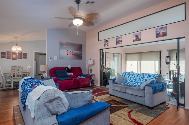 living room featuring ceiling fan with notable chandelier, dark hardwood / wood-style floors, and vaulted ceiling