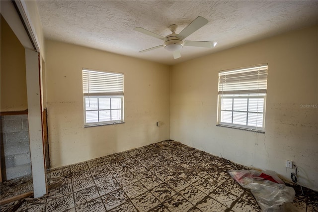 unfurnished room featuring ceiling fan, a healthy amount of sunlight, and a textured ceiling