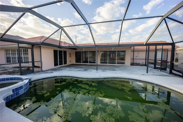 back of house featuring a swimming pool with hot tub, a patio area, and glass enclosure