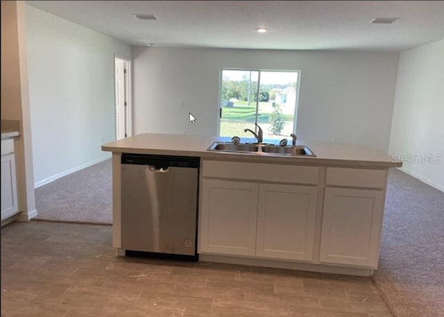 kitchen featuring stainless steel dishwasher, light colored carpet, white cabinetry, and sink