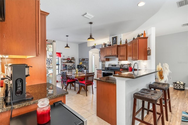 kitchen featuring kitchen peninsula, pendant lighting, stainless steel electric stove, and dark stone counters