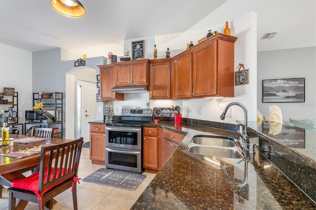 kitchen with dark stone countertops, sink, light tile patterned floors, and double oven range