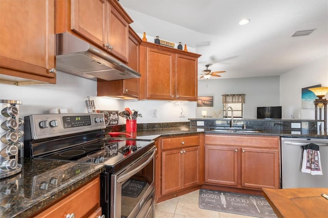 kitchen featuring sink, ceiling fan, dark stone countertops, light tile patterned floors, and stainless steel appliances