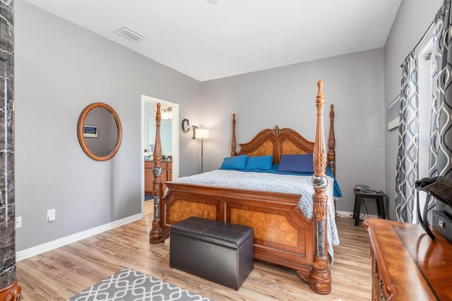 bedroom with ensuite bath and light wood-type flooring