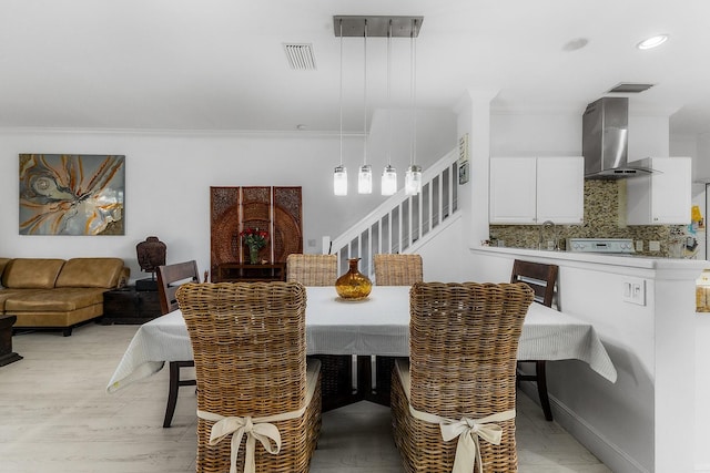 dining room featuring light hardwood / wood-style floors, ornamental molding, and sink