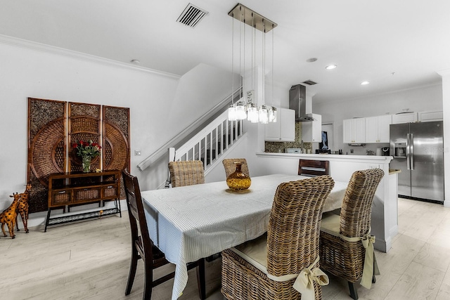 dining room featuring crown molding and light hardwood / wood-style floors