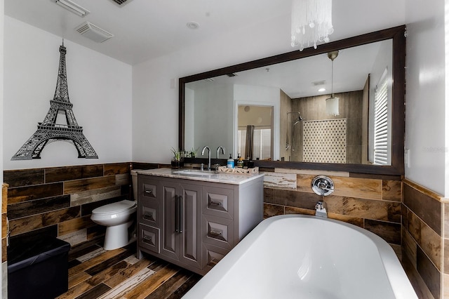 full bathroom featuring vanity, hardwood / wood-style flooring, tile walls, independent shower and bath, and toilet