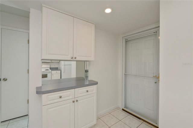 kitchen with electric range, white cabinets, and light tile patterned floors