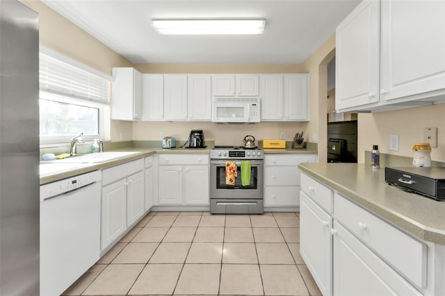 kitchen featuring light tile patterned floors, white appliances, white cabinetry, and sink