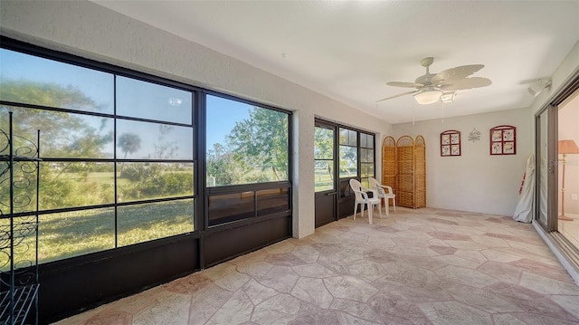 unfurnished sunroom featuring ceiling fan