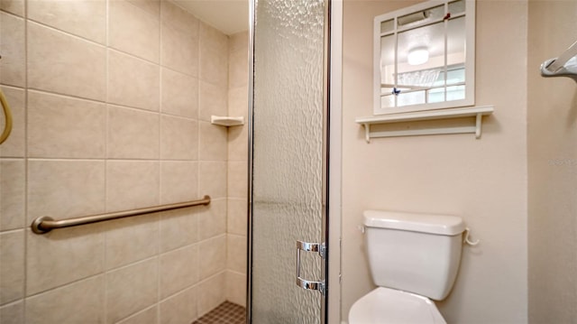 bathroom featuring toilet and a shower with door