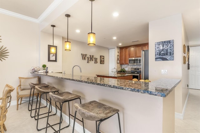 kitchen featuring kitchen peninsula, pendant lighting, dark stone counters, decorative backsplash, and appliances with stainless steel finishes