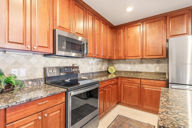 kitchen featuring light tile patterned floors, stainless steel appliances, tasteful backsplash, and dark stone countertops