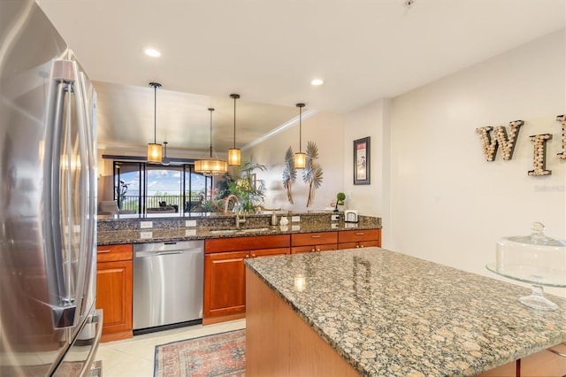 kitchen with pendant lighting, stone counters, sink, ornamental molding, and appliances with stainless steel finishes