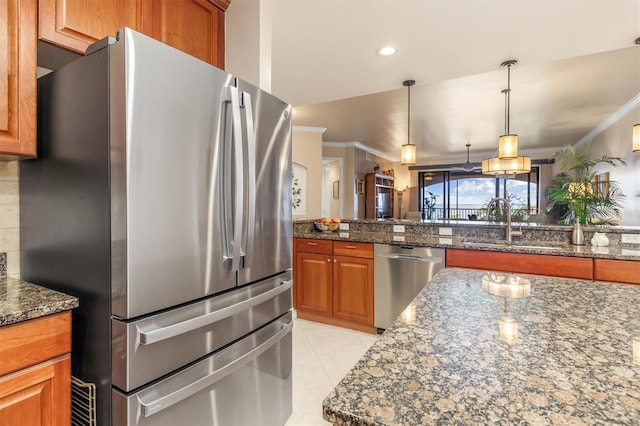 kitchen with stainless steel appliances, crown molding, and dark stone counters