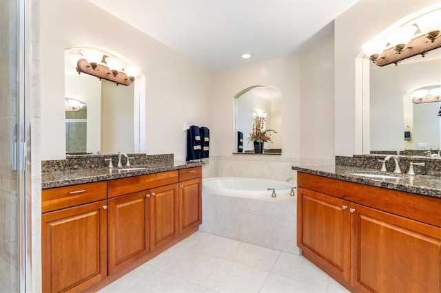 bathroom featuring tiled tub, tile patterned flooring, and vanity