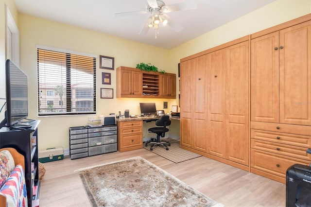 office with light wood-type flooring, ceiling fan, and built in desk