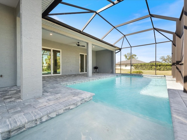 view of swimming pool featuring a patio, glass enclosure, and ceiling fan