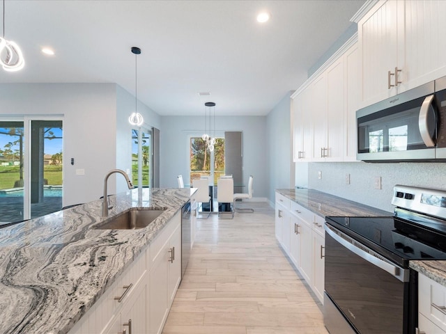 kitchen with sink, light hardwood / wood-style flooring, light stone countertops, white cabinetry, and stainless steel appliances