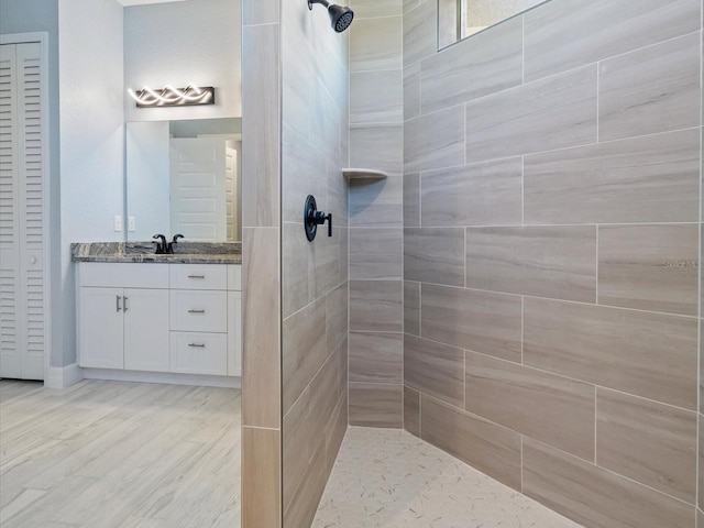 bathroom with a tile shower, hardwood / wood-style floors, and vanity