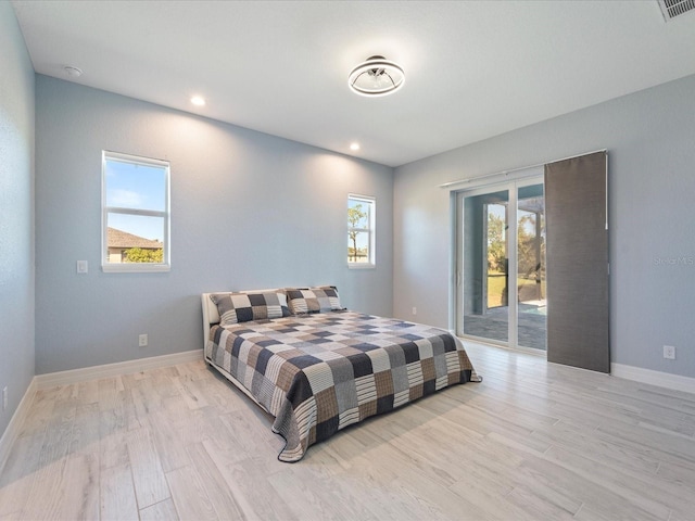 bedroom with access to outside, multiple windows, and light hardwood / wood-style floors