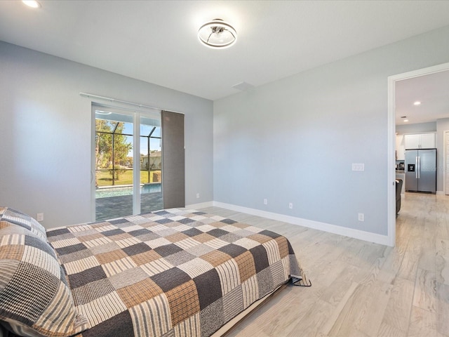 bedroom with access to exterior, stainless steel fridge, and light hardwood / wood-style flooring