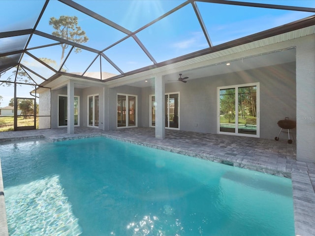 view of swimming pool with glass enclosure, ceiling fan, and a patio area