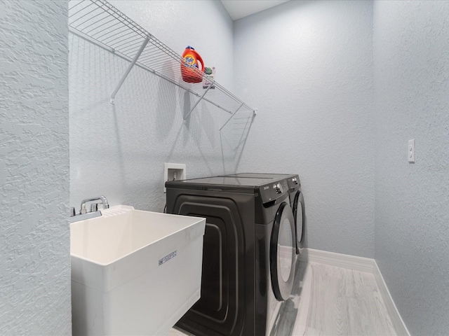 laundry area with separate washer and dryer, hardwood / wood-style flooring, and sink