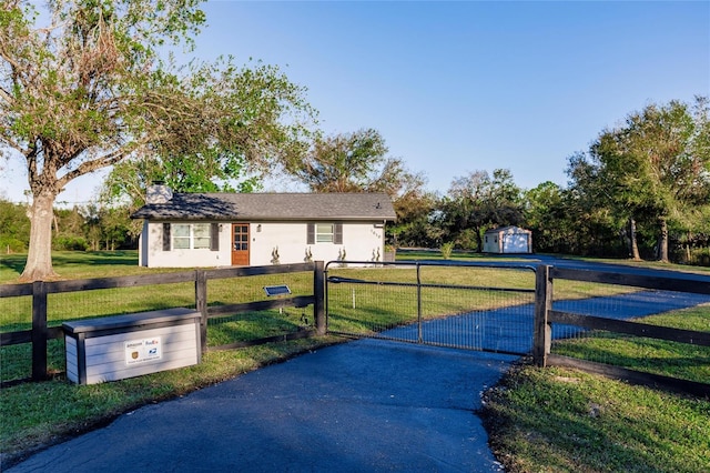 view of gate featuring a lawn and a storage unit