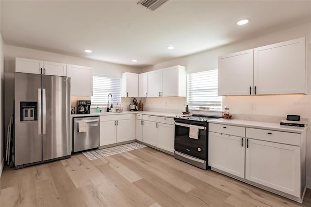 1010 Robinhood Dr, Punta Gorda, FL 33982 - kitchen featuring stainless steel appliances, a sink, white cabinetry, light wood-style floors, and light countertops