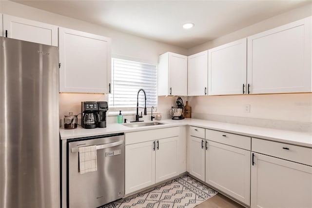 kitchen with appliances with stainless steel finishes, white cabinetry, and sink