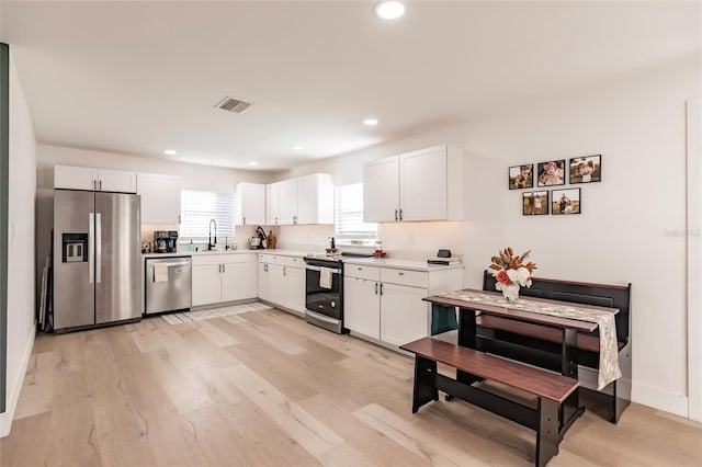 kitchen with white cabinetry, sink, stainless steel appliances, and light wood-type flooring