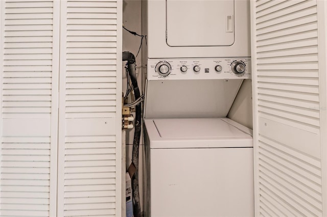 clothes washing area with stacked washing maching and dryer