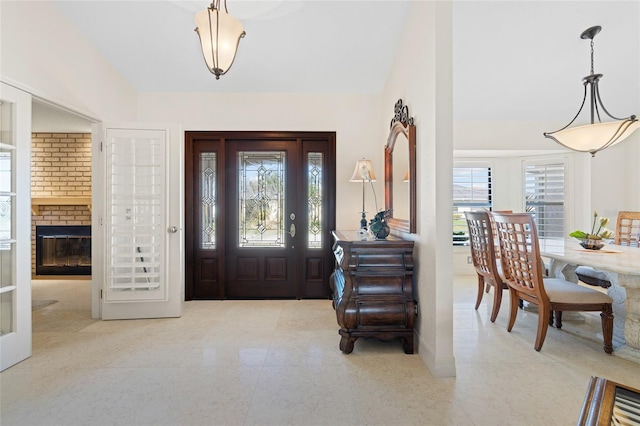 foyer entrance with vaulted ceiling and a brick fireplace