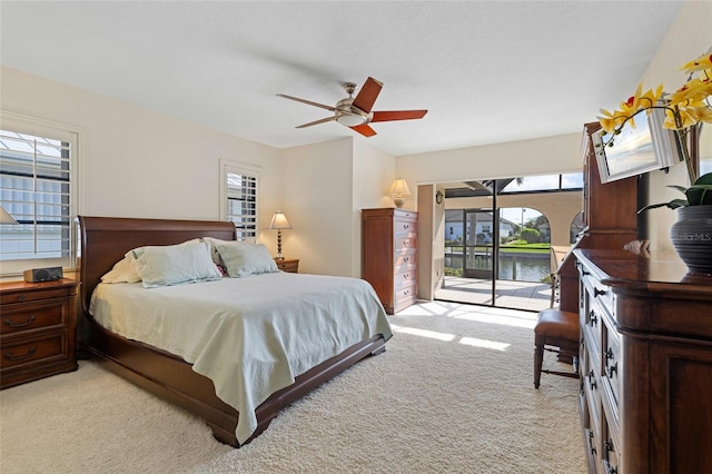 carpeted bedroom featuring ceiling fan, a water view, and access to outside