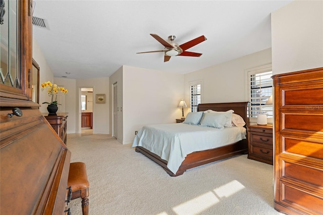 carpeted bedroom featuring ensuite bath, ceiling fan, and a closet