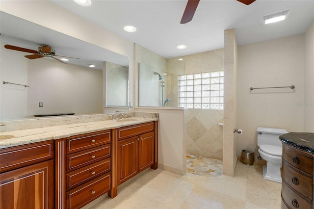 bathroom with a tile shower, vanity, toilet, and ceiling fan