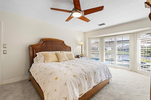 bedroom with ceiling fan, access to exterior, light colored carpet, and a textured ceiling