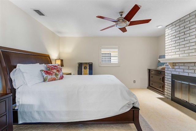 bedroom featuring light carpet, a brick fireplace, and ceiling fan