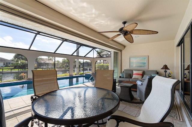 sunroom with ceiling fan, plenty of natural light, a water view, and a pool