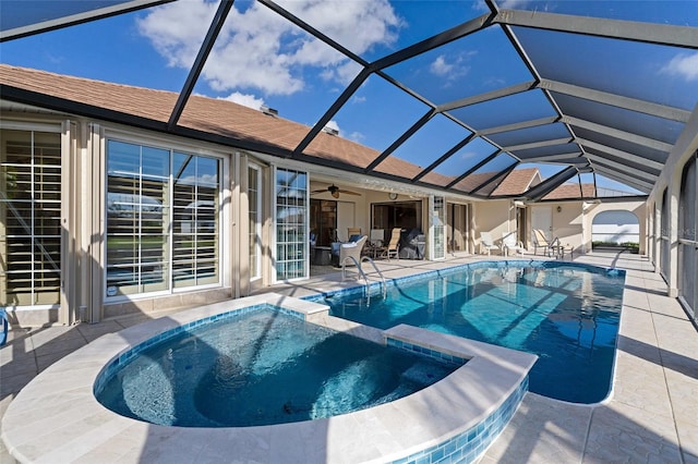 view of pool with an in ground hot tub, a patio, glass enclosure, and ceiling fan