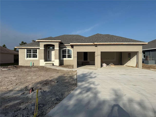 view of front of home featuring driveway, an attached garage, roof with shingles, and stucco siding