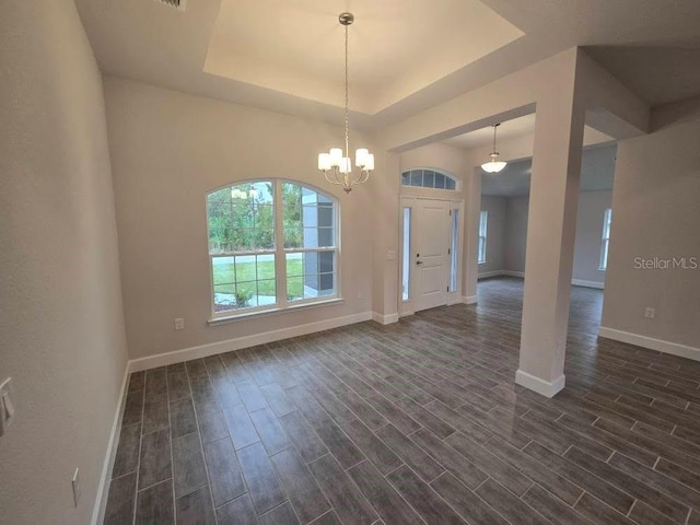 interior space with wood tiled floor, baseboards, a raised ceiling, and a chandelier