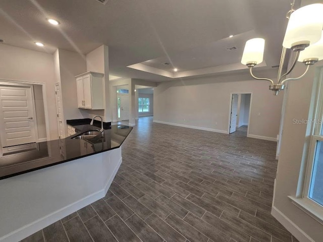 kitchen with dark countertops, wood tiled floor, white cabinets, and a sink